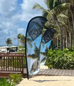 Banderas publicitarias con palmeras y playa en Cancún, México.
